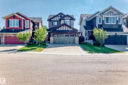 Three distinct two-story homes with attached garages, each featuring a concrete driveway and a manicured front lawn - 5147 Crabapple Link Sw, Edmonton, AB - Outdoor With Facade