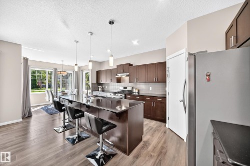 Spacious kitchen with a central island, dark cabinetry, and integrated stainless steel appliances - 5147 Crabapple Link Sw, Edmonton, AB - Indoor Photo Showing Kitchen With Upgraded Kitchen