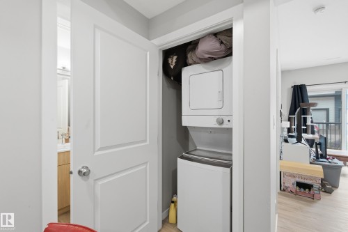 Stackable washer and dryer within a dedicated closet - #106 856 Secord Bv Nw Nw, Edmonton, AB - Indoor Photo Showing Laundry Room