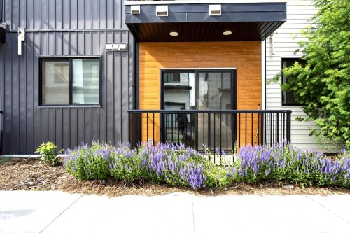 Modern exterior featuring dark vertical siding and a private balcony with wood-finish paneling - #106 856 Secord Bv Nw Nw, Edmonton, AB - Outdoor With Exterior