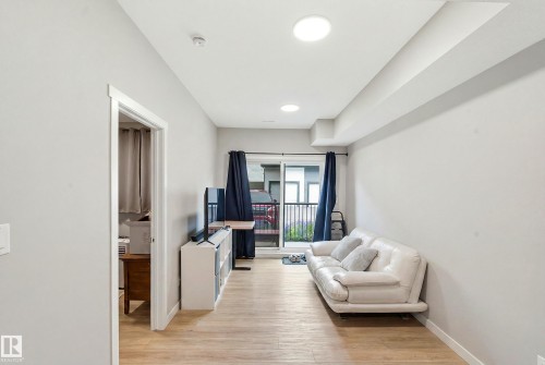 Recessed ceiling lighting, wood-finish flooring, light-colored walls, sliding glass door, and a balcony with metal railing - #106 856 Secord Bv Nw Nw, Edmonton, AB - Indoor