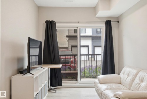 Sliding glass door, light wood-finish flooring, and a neutral wall color - #106 856 Secord Bv Nw Nw, Edmonton, AB - Indoor
