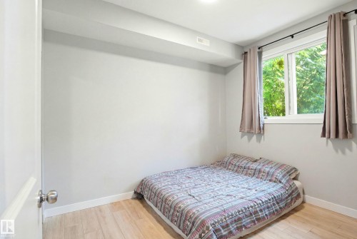 Light wood-finish flooring, white trim, and a window with natural light - #106 856 Secord Bv Nw Nw, Edmonton, AB - Indoor Photo Showing Bedroom