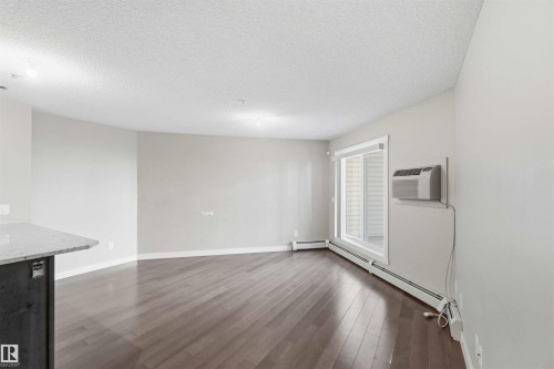 Spacious room featuring wood-finish flooring, light grey wall paint, and a textured white ceiling - #114 2207 44 Av Nw, Edmonton, AB - Indoor Photo Showing Other Room