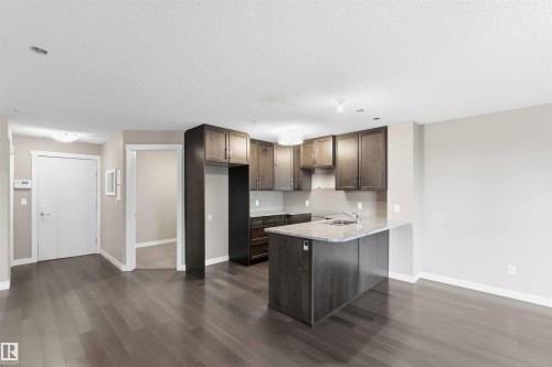 Kitchen featuring dark wood-finish cabinetry, granite countertops, and a stainless steel sink - #114 2207 44 Av Nw, Edmonton, AB - Indoor Photo Showing Kitchen