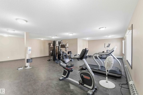 Dedicated fitness area featuring durable dark flooring, multiple windows, and recessed ceiling lighting - #114 2207 44 Av Nw, Edmonton, AB - Indoor Photo Showing Gym Room