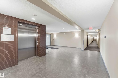 Contemporary elevator lobby featuring a stainless steel elevator door and brown subway tile surround - #114 2207 44 Av Nw, Edmonton, AB - Indoor Photo Showing Other Room