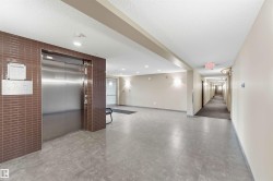 Contemporary elevator lobby featuring a stainless steel elevator door and brown subway tile surround - 