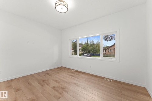 Bright room featuring wood-finish flooring, white walls, a flush-mount ceiling light fixture, and a multi-pane window - 10825 93 Street Nw, Edmonton, AB - Indoor Photo Showing Other Room