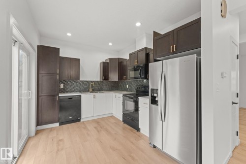 Kitchen featuring light wood-finish flooring, recessed lighting, two-tone cabinetry, a mosaic tile backsplash, and stainless steel appliances - 10825 93 Street Nw, Edmonton, AB - Indoor Photo Showing Kitchen With Upgraded Kitchen