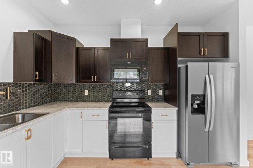Kitchen featuring two-tone cabinetry, a tile backsplash, stainless steel sink, and stainless steel refrigerator - 10825 93 Street Nw, Edmonton, AB - Indoor Photo Showing Kitchen With Upgraded Kitchen