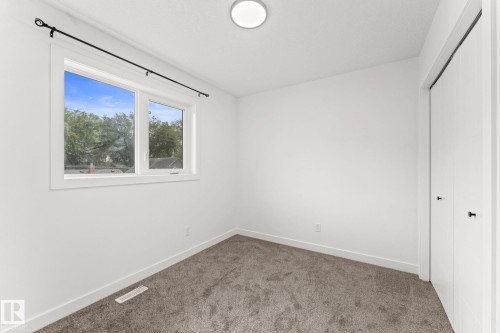 Bright room featuring a flush-mount ceiling light, white walls, and gray carpet flooring - 10825 93 Street Nw, Edmonton, AB - Indoor Photo Showing Other Room