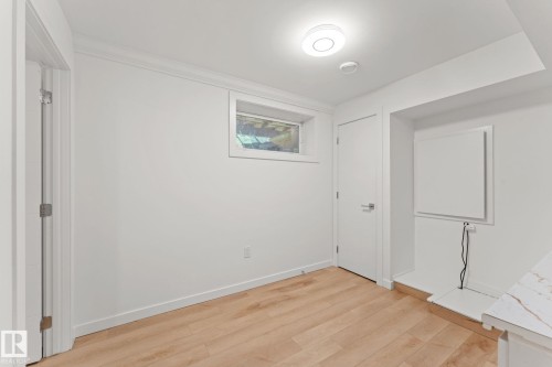 Wood-finish flooring, white walls, flush-mount ceiling light, and a window for natural light - 10825 93 Street Nw, Edmonton, AB - Indoor Photo Showing Other Room