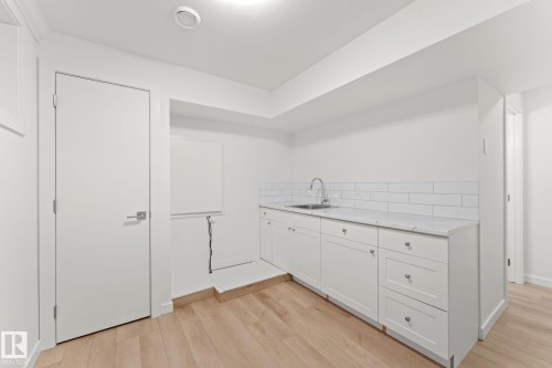White cabinetry with an undermount sink, a chrome faucet, and subway tile backsplash - 10825 93 Street Nw, Edmonton, AB - Indoor Photo Showing Other Room