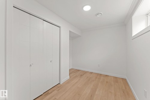 Recessed ceiling lighting, crown molding, wood-finish flooring, and white bi-fold closet doors - 10825 93 Street Nw, Edmonton, AB - Indoor Photo Showing Other Room