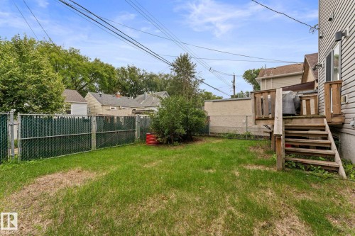 Rear exterior with wood deck and staircase, chain-link fencing with privacy slats, and mature landscaping - 10825 93 Street Nw, Edmonton, AB - Outdoor