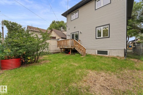 Rear exterior featuring gray siding, a wood deck with stairs, and a ground-level window - 10825 93 Street Nw, Edmonton, AB - Outdoor
