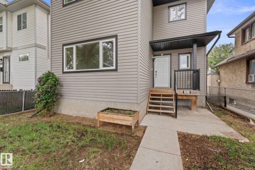 Gray horizontal siding with black trim windows, covered entry, and wood steps - 10825 93 Street Nw, Edmonton, AB - Outdoor