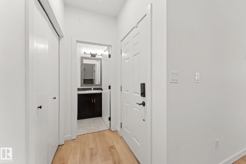 Entryway featuring light wood-finish flooring, white paneled doors, and a dark wood-finish vanity with a vessel sink and tile backsplash - 10825 93 Street Nw, Edmonton, AB - Indoor Photo Showing Other Room