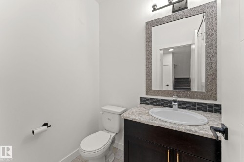 Vanity with a single basin, stone-finish countertop, and dark wood-finish cabinetry - 10825 93 Street Nw, Edmonton, AB - Indoor Photo Showing Bathroom