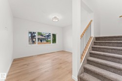 Wood-finish flooring, white walls, and a multi-pane window illuminate the space - 