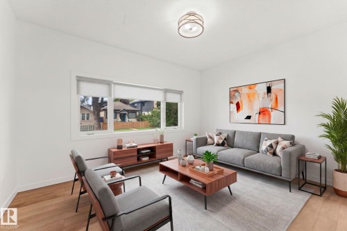Spacious living area featuring light wood-finish flooring, a contemporary semi-flush mount ceiling light, and ample natural light from the expansive window - 10825 93 Street Nw, Edmonton, AB - Indoor Photo Showing Living Room