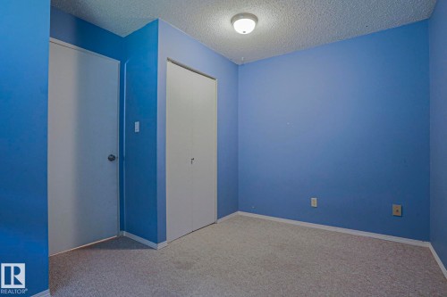 Carpeted flooring, two white doors, blue walls, and a ceiling-mounted light fixture - #45 1651 46 St Nw, Edmonton, AB - Indoor Photo Showing Other Room