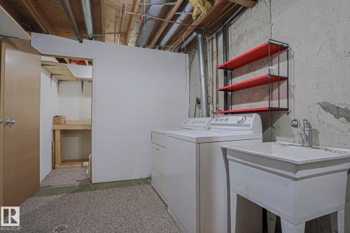 Laundry area with a utility sink, wall-mounted shelving, and carpet flooring - #45 1651 46 St Nw, Edmonton, AB - Indoor Photo Showing Laundry Room