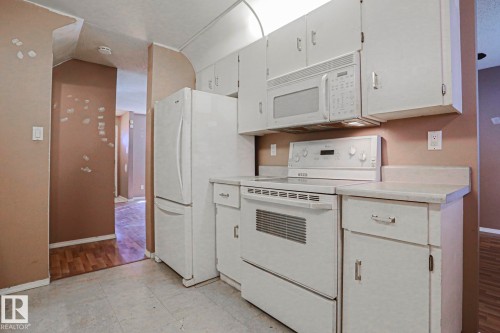 Kitchen featuring white cabinetry, a built-in microwave, an electric range, and a refrigerator - #45 1651 46 St Nw, Edmonton, AB - Indoor Photo Showing Kitchen