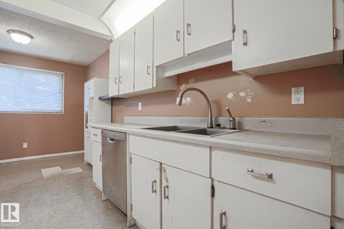 White cabinetry, dual basin sink, stainless steel dishwasher, and a window - #45 1651 46 St Nw, Edmonton, AB - Indoor Photo Showing Kitchen With Double Sink