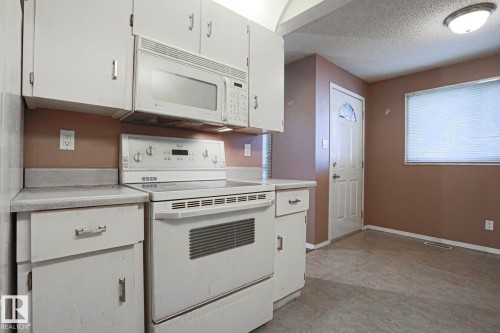 Kitchen space featuring white cabinetry, an electric range, an over-the-range microwave, and light-colored countertops - #45 1651 46 St Nw, Edmonton, AB - Indoor Photo Showing Kitchen