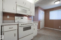 Kitchen space featuring white cabinetry, an electric range, an over-the-range microwave, and light-colored countertops - 
