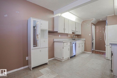 Kitchen with white cabinetry, light-toned countertops, and a stainless steel dishwasher - #45 1651 46 St Nw, Edmonton, AB - Indoor Photo Showing Kitchen