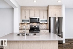 Kitchen island with a double basin stainless steel sink, wood-finish cabinetry, stainless steel appliances, and a tiled backsplash - 