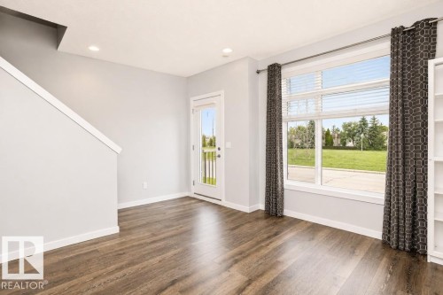 Wood-finish flooring, recessed lighting, expansive window with blinds, and white trim - #6 215 Saddleback Rd Nw, Edmonton, AB - Indoor Photo Showing Other Room
