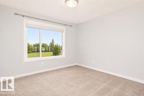 Neutral wall finishes, recessed ceiling light fixture, large window with roller shade, and light-toned carpeting - #6 215 Saddleback Rd Nw, Edmonton, AB - Indoor Photo Showing Other Room