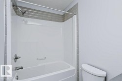 Tub/shower combination with a white surround, gray tile accent, and polished chrome fixtures - 