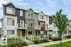 Contemporary townhome exterior with varied siding textures, private balconies, individual entrances, white picket fencing, and concrete walkways - 