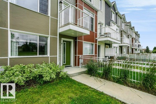 Contemporary multi-level facade with a vibrant green entry door and a private balcony - #6 215 Saddleback Rd Nw, Edmonton, AB - Outdoor
