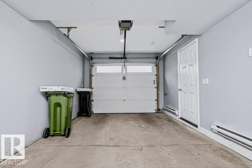 Attached garage with concrete flooring, finished walls, and a panel door - #6 215 Saddleback Rd Nw, Edmonton, AB - Indoor Photo Showing Garage