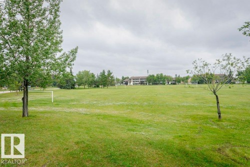 Expansive green space featuring scattered trees and distant structures - #6 215 Saddleback Rd Nw, Edmonton, AB - Outdoor With View