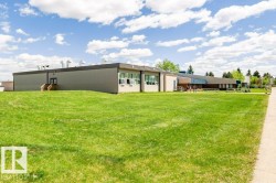 Expansive green lawn, multi-level building structure, multiple windows, flat roof, and a paved walkway - 