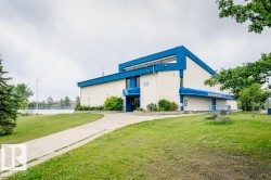 Building exterior with blue architectural accents and light-colored siding, featuring a paved walkway - 