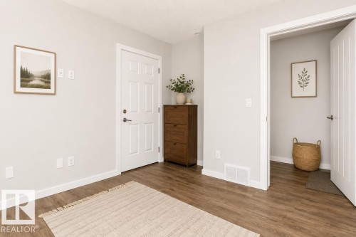 Wood-finish flooring throughout, bright white walls, and a white paneled door - #6 215 Saddleback Rd Nw, Edmonton, AB - Indoor Photo Showing Other Room