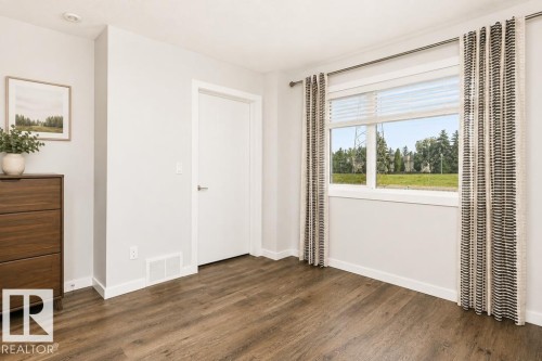 Wood-finish flooring, white trim, recessed lighting, white panel door, and a large window - #6 215 Saddleback Rd Nw, Edmonton, AB - Indoor Photo Showing Other Room