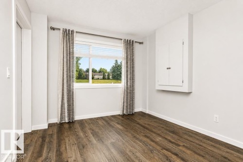 Wood-finish flooring, white walls, and a built-in storage cabinet - #6 215 Saddleback Rd Nw, Edmonton, AB - Indoor Photo Showing Other Room