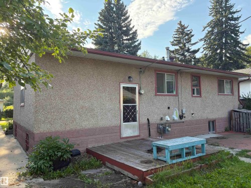 Charming single-story home featuring stucco exterior with contrasting brick foundation trim, multiple windows with wood frames, and an attached entry door - 10845 140 Street Nw, Edmonton, AB - Outdoor