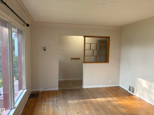 Bright, open living space with wood-finish flooring, abundant natural light from sliding glass doors, and neutral wall finishes - 10845 140 Street Nw, Edmonton, AB - Indoor Photo Showing Other Room