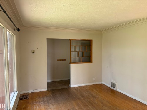 Spacious living area featuring warm wood-finish flooring, neutral walls, and abundant natural light from sliding glass doors - 10845 140 Street Nw, Edmonton, AB - Indoor Photo Showing Other Room