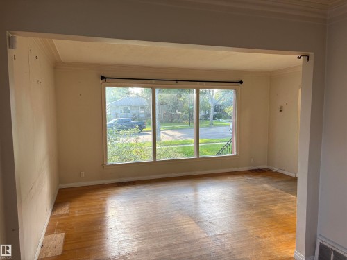 Triple pane window, wood-finish flooring, coved ceiling, crown molding, and an open entryway - 10845 140 Street Nw, Edmonton, AB - Indoor Photo Showing Other Room